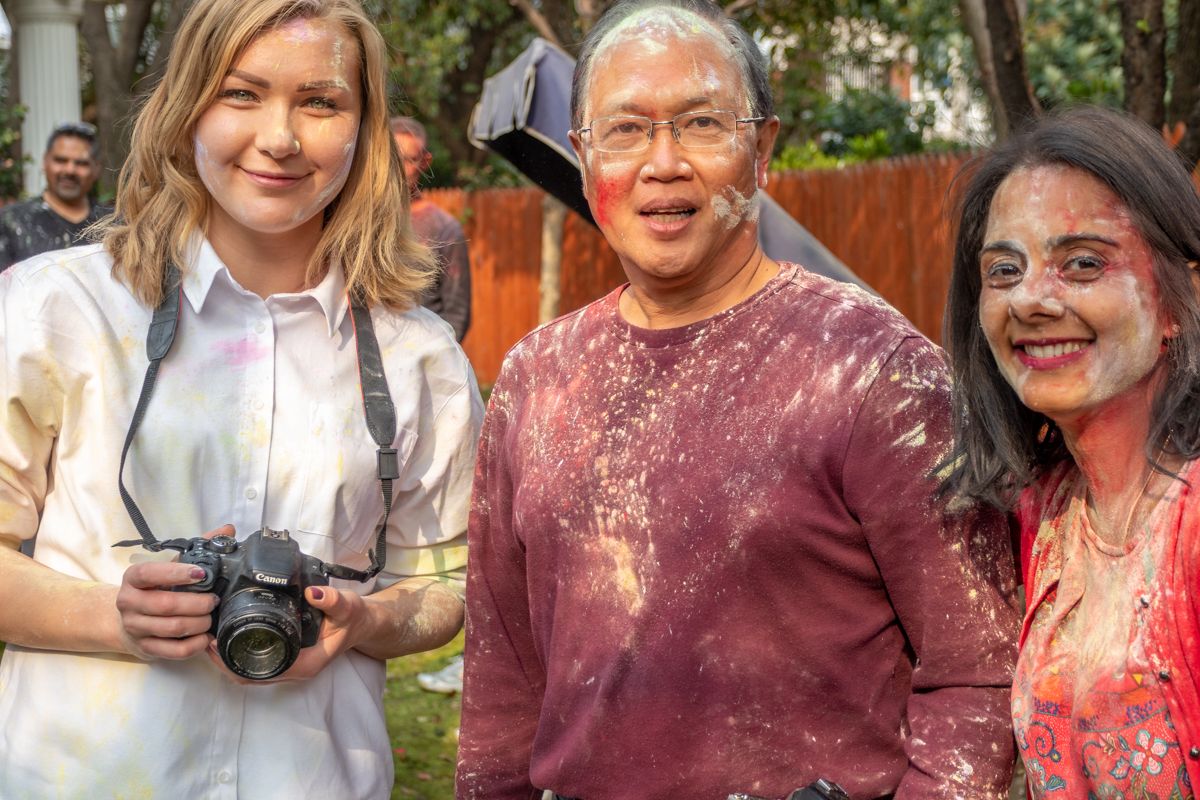 Group celebrating Holi festival with colorful powder and camera.