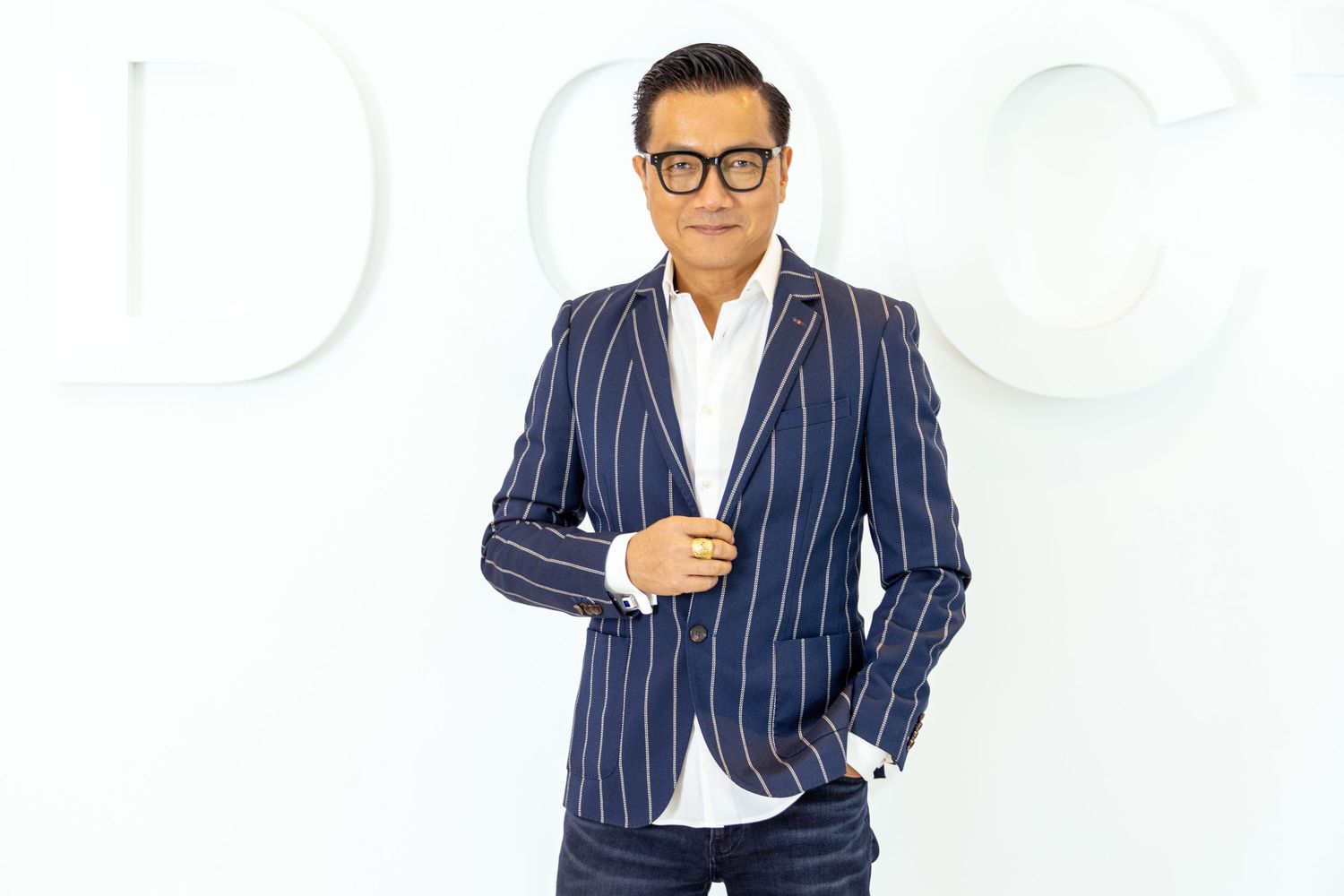 Professional wearing a navy pinstripe suit and glasses poses against white background in three different stances.