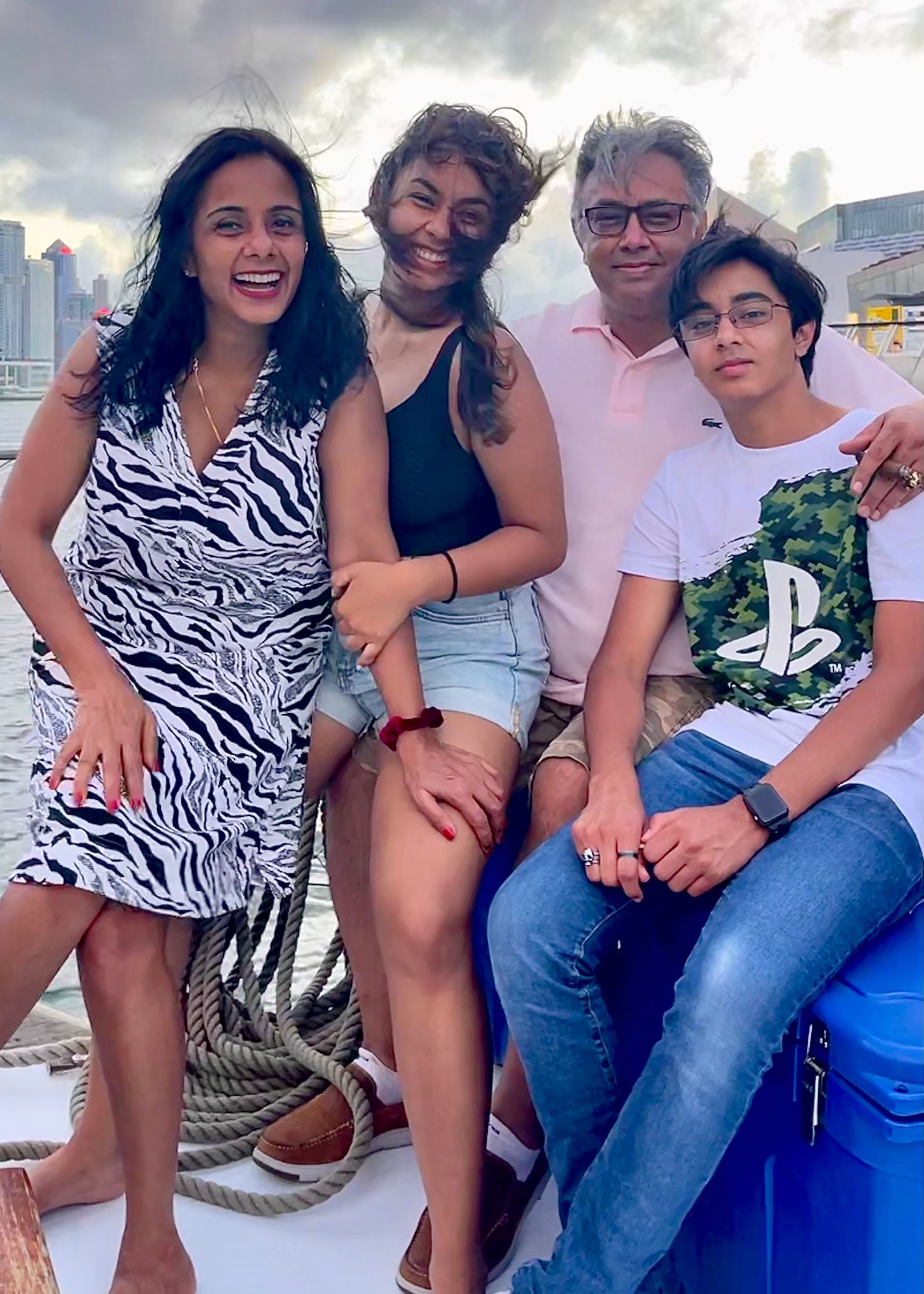 A family sitting together on a boat wearing casual summer outfits with zebra prints and denim.