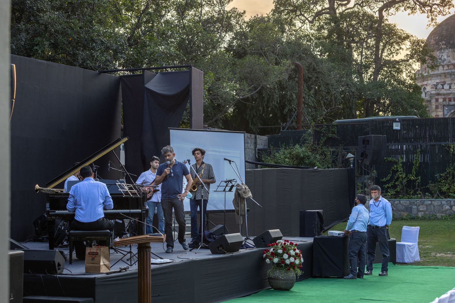 Jazz ensemble performs on outdoor stage during sunset with piano and instruments visible.
