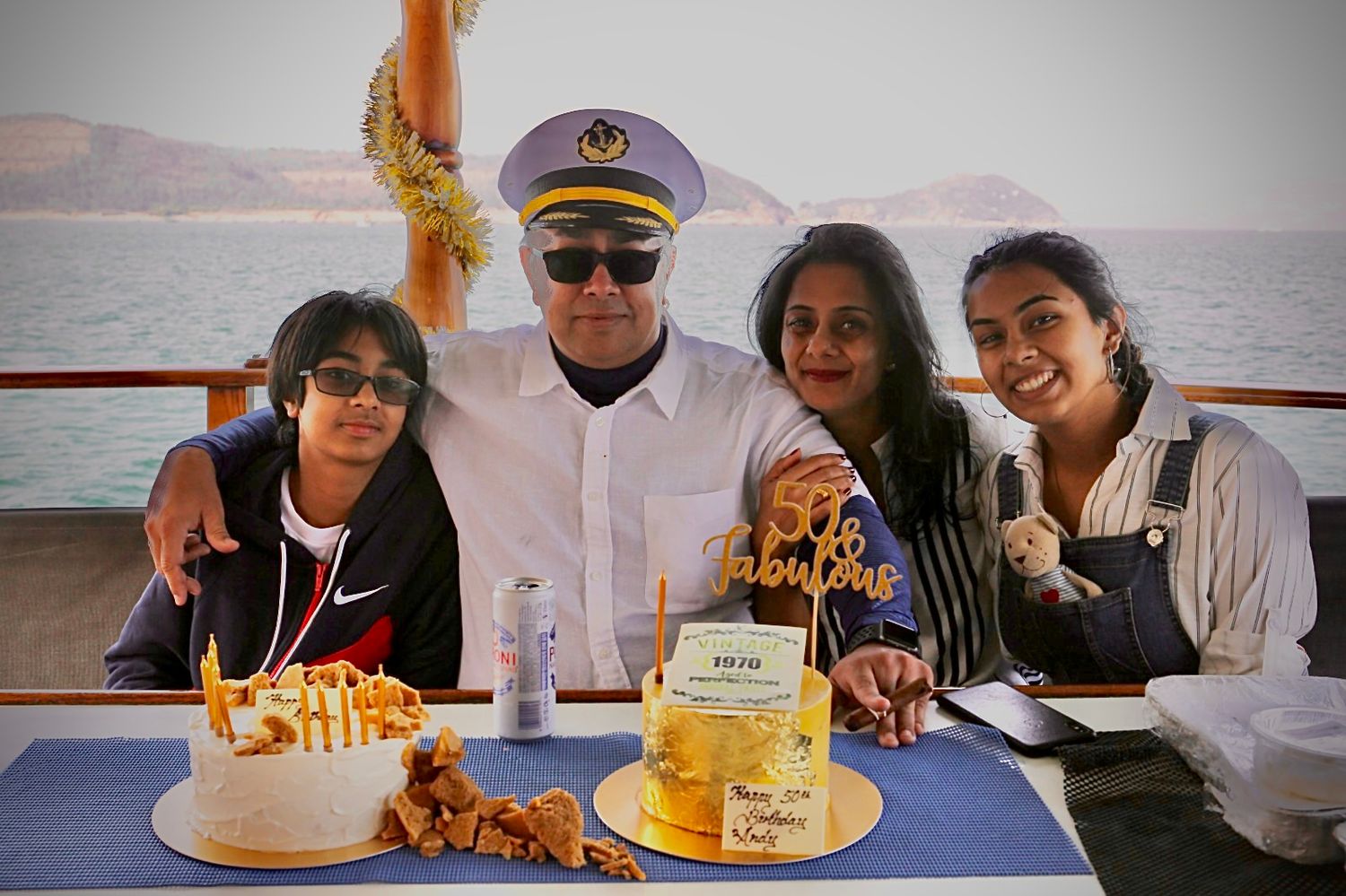 Group enjoying a celebratory meal with cake and food on boat.