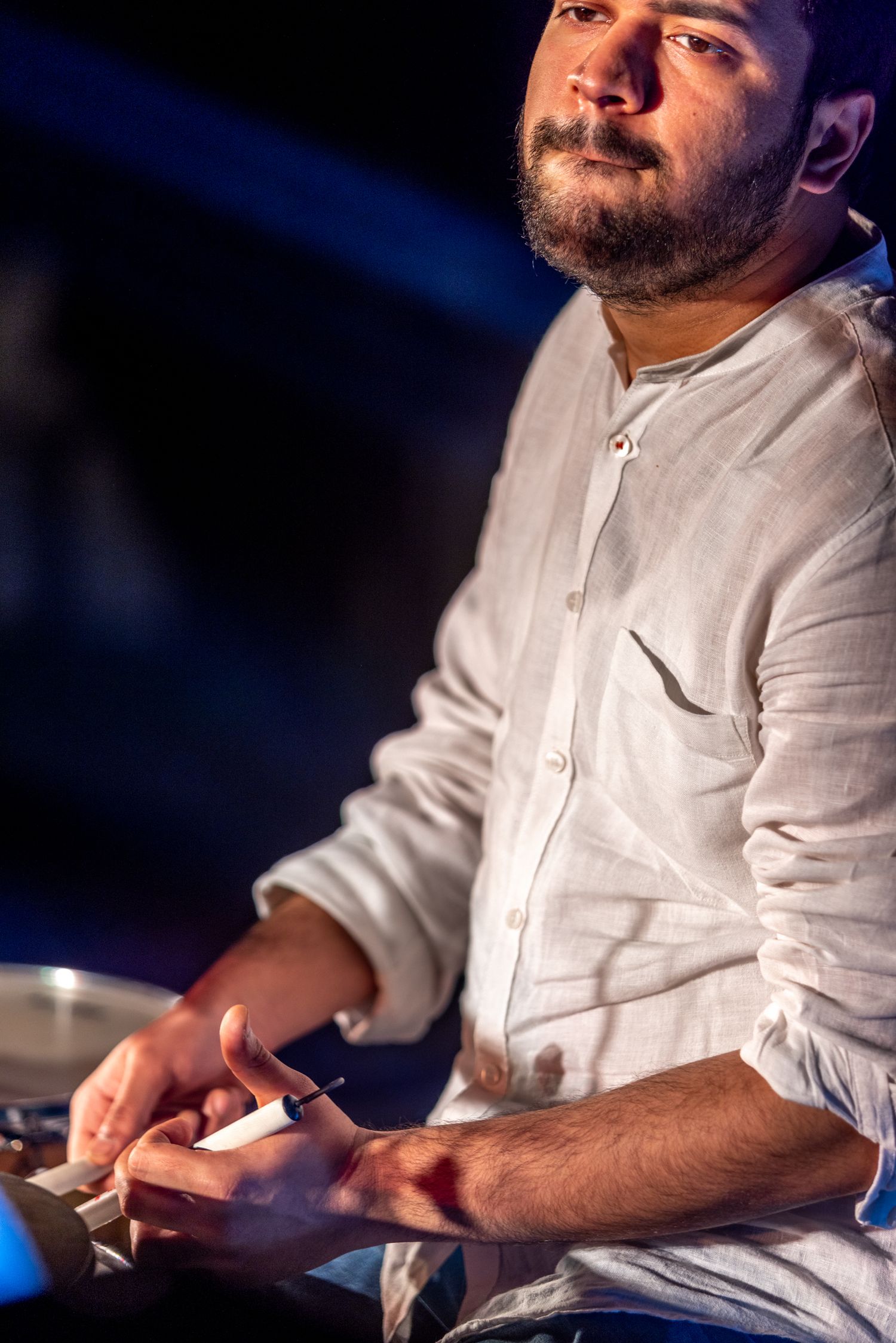 Musician in white shirt performing with dramatic blue stage lighting.