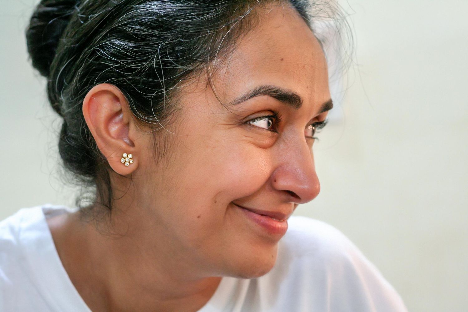 Side profile portrait of person in white t-shirt smiling warmly.