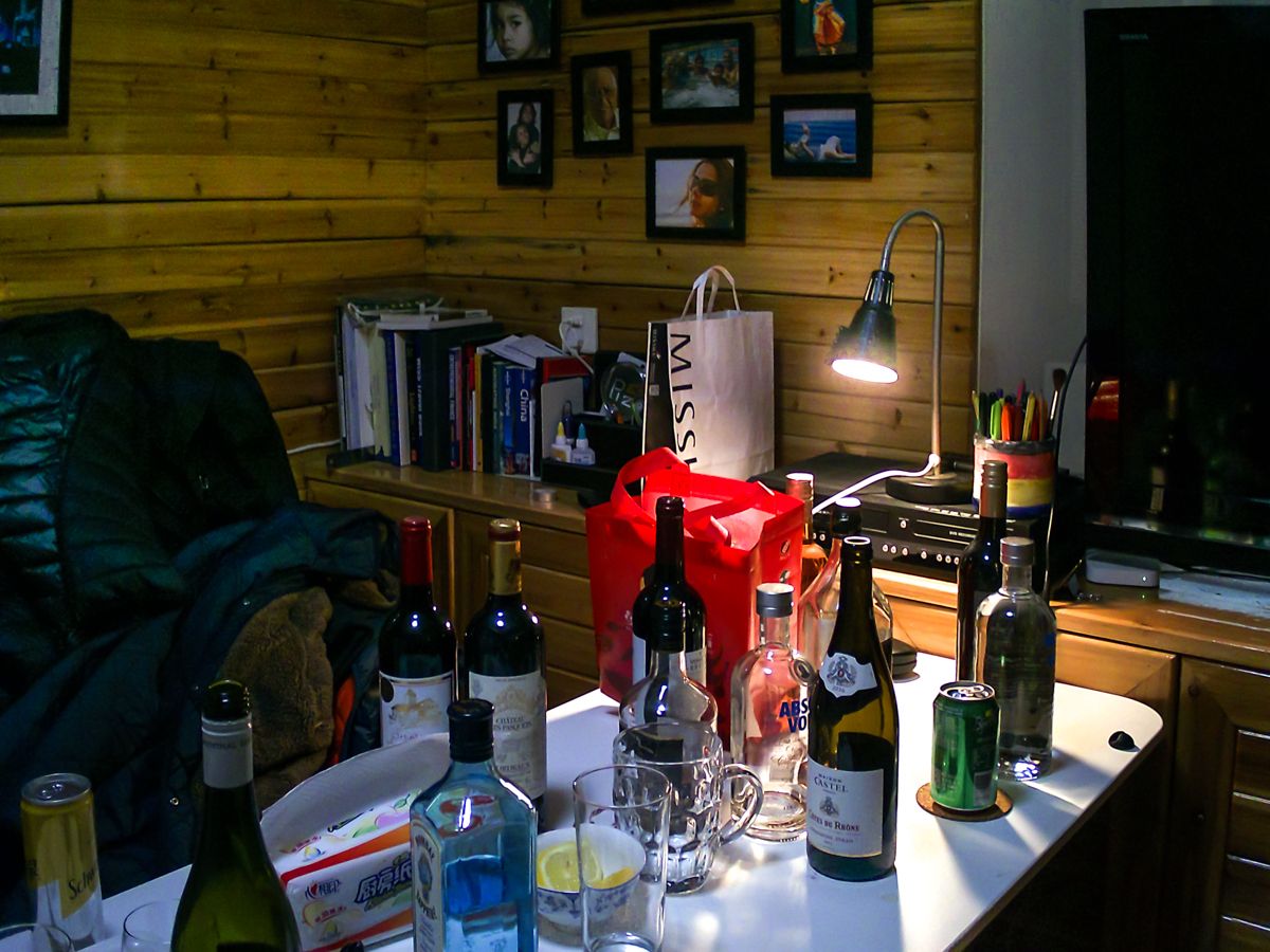 Assorted liquor bottles and a red robot figure displayed on wooden table with mood lighting.
