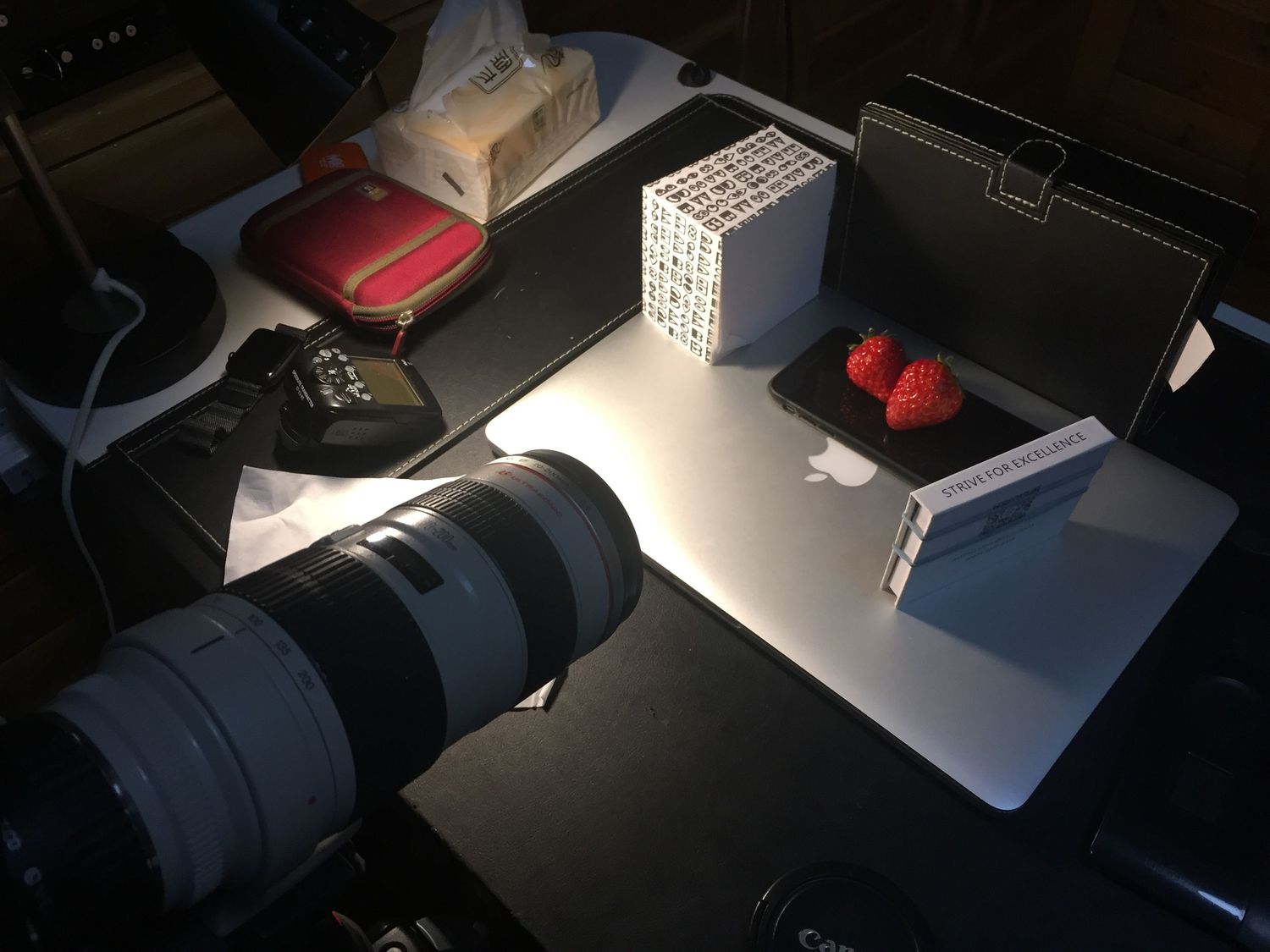 Photography equipment with telephoto lens and red lights arranged on reflective surface.