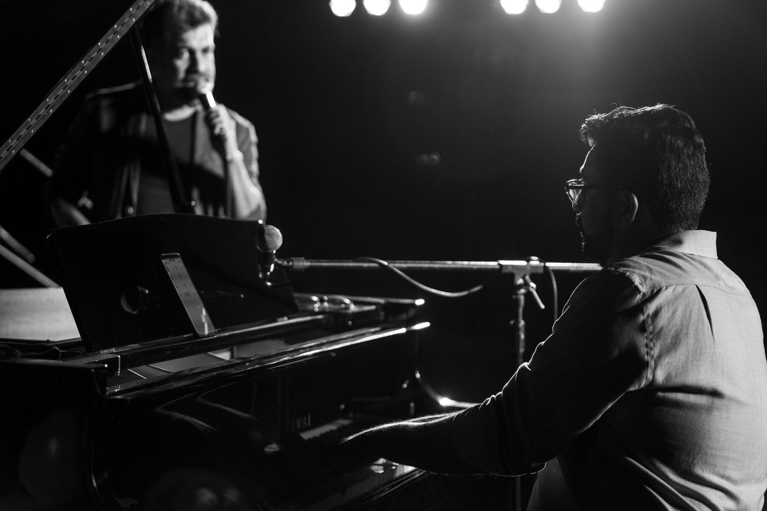 Black and white shot of musicians performing at piano during intimate concert.