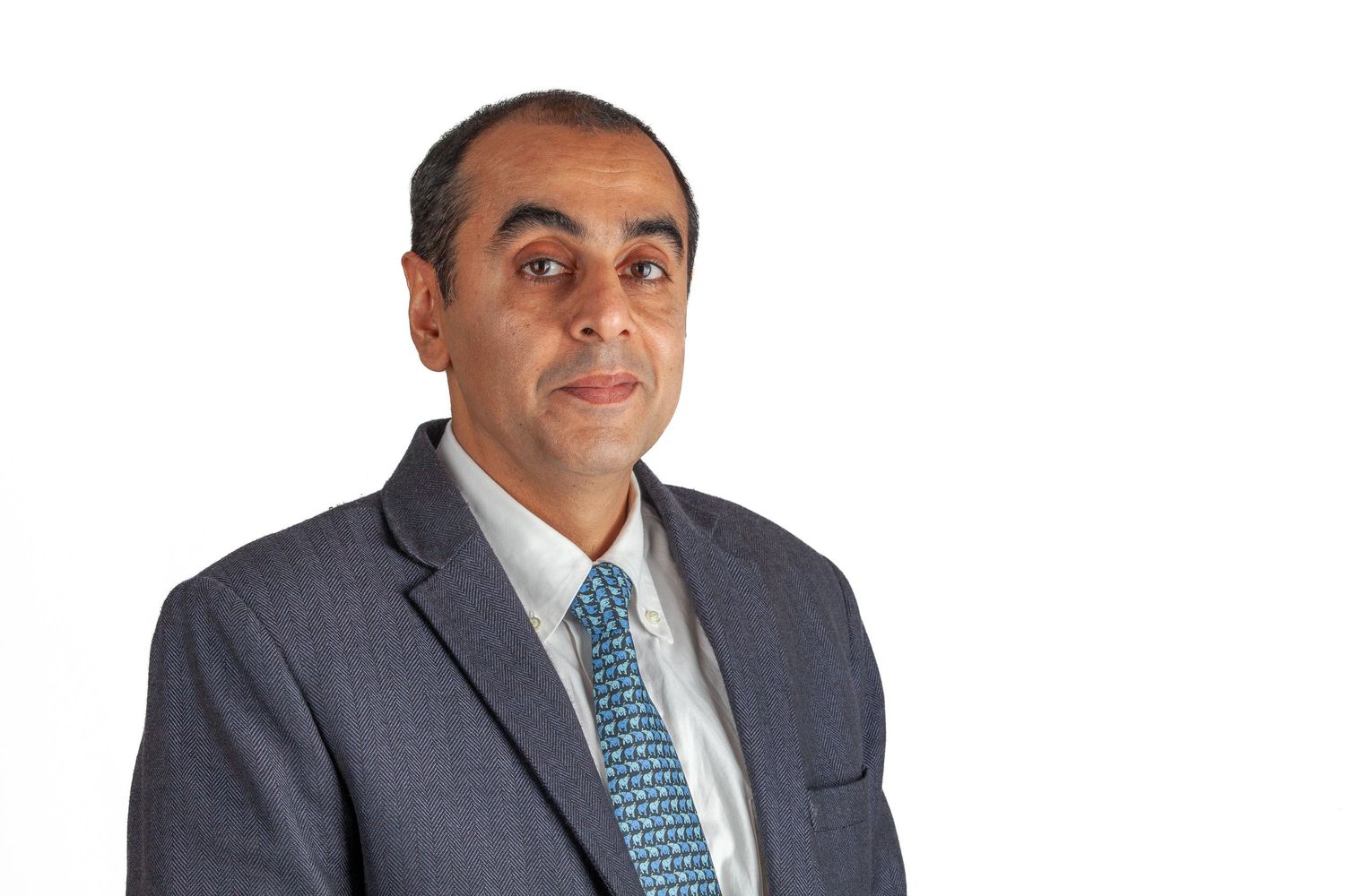 Professional headshot of person in dark business suit with patterned tie.