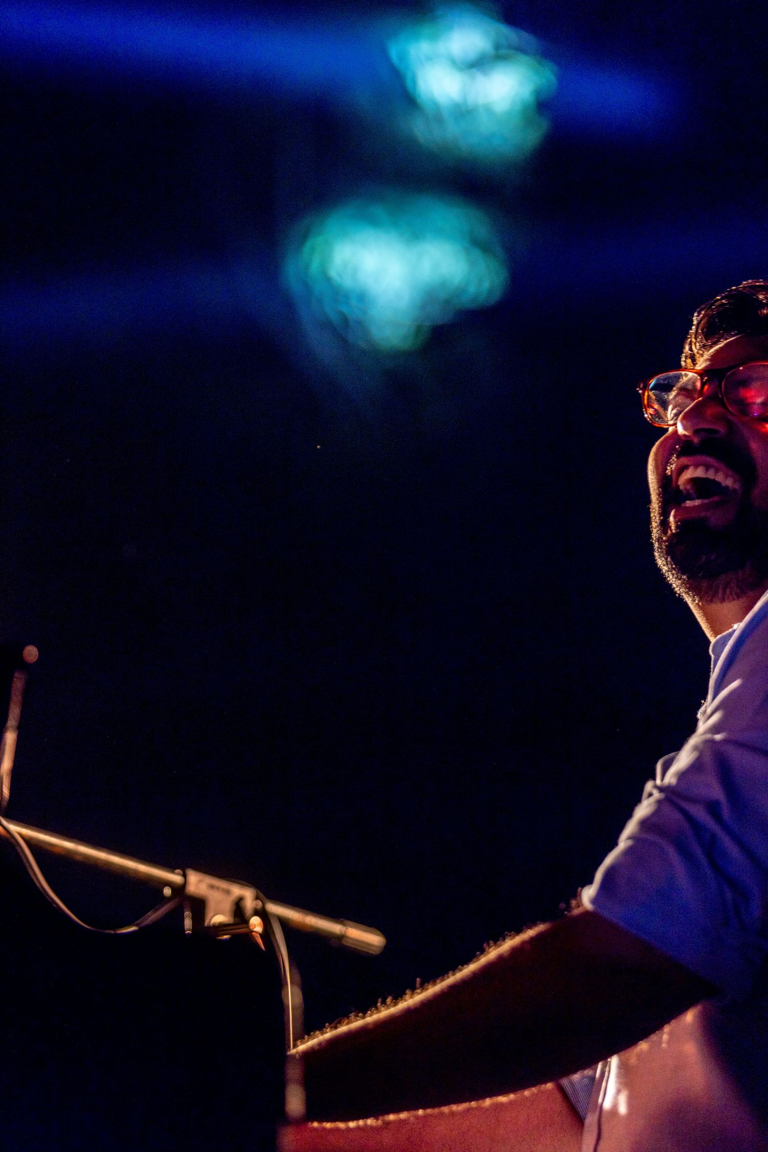 Dramatic close-up of a performer with ethereal blue lights floating above.