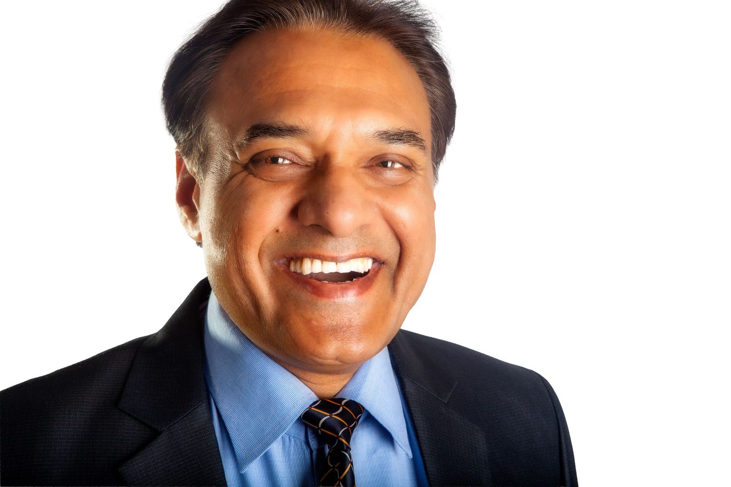Professional headshot of a smiling person wearing a dark suit and blue tie against a neutral background.