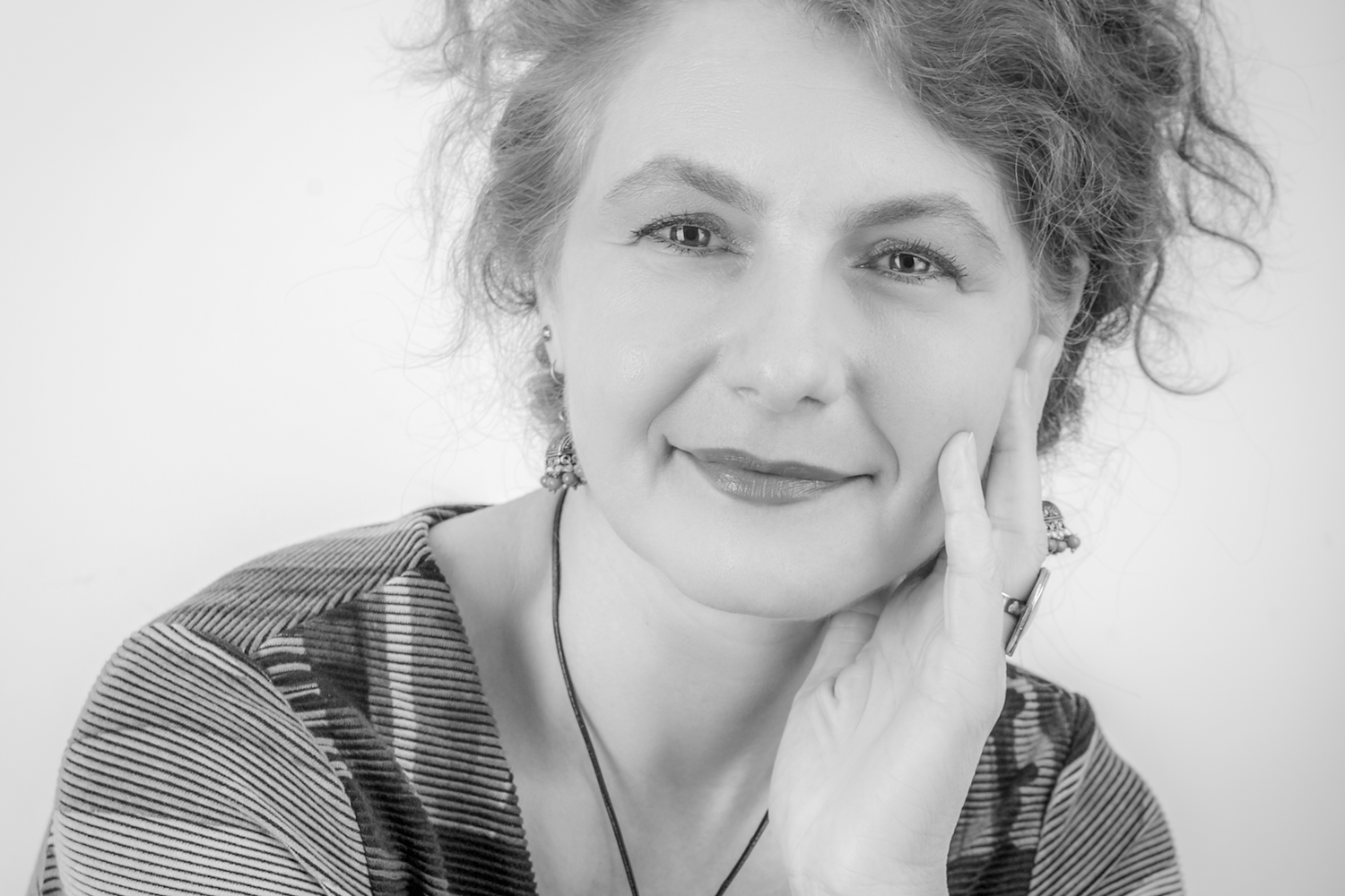 A series of black and white headshot portraits showing someone with curly hair in different poses and expressions.