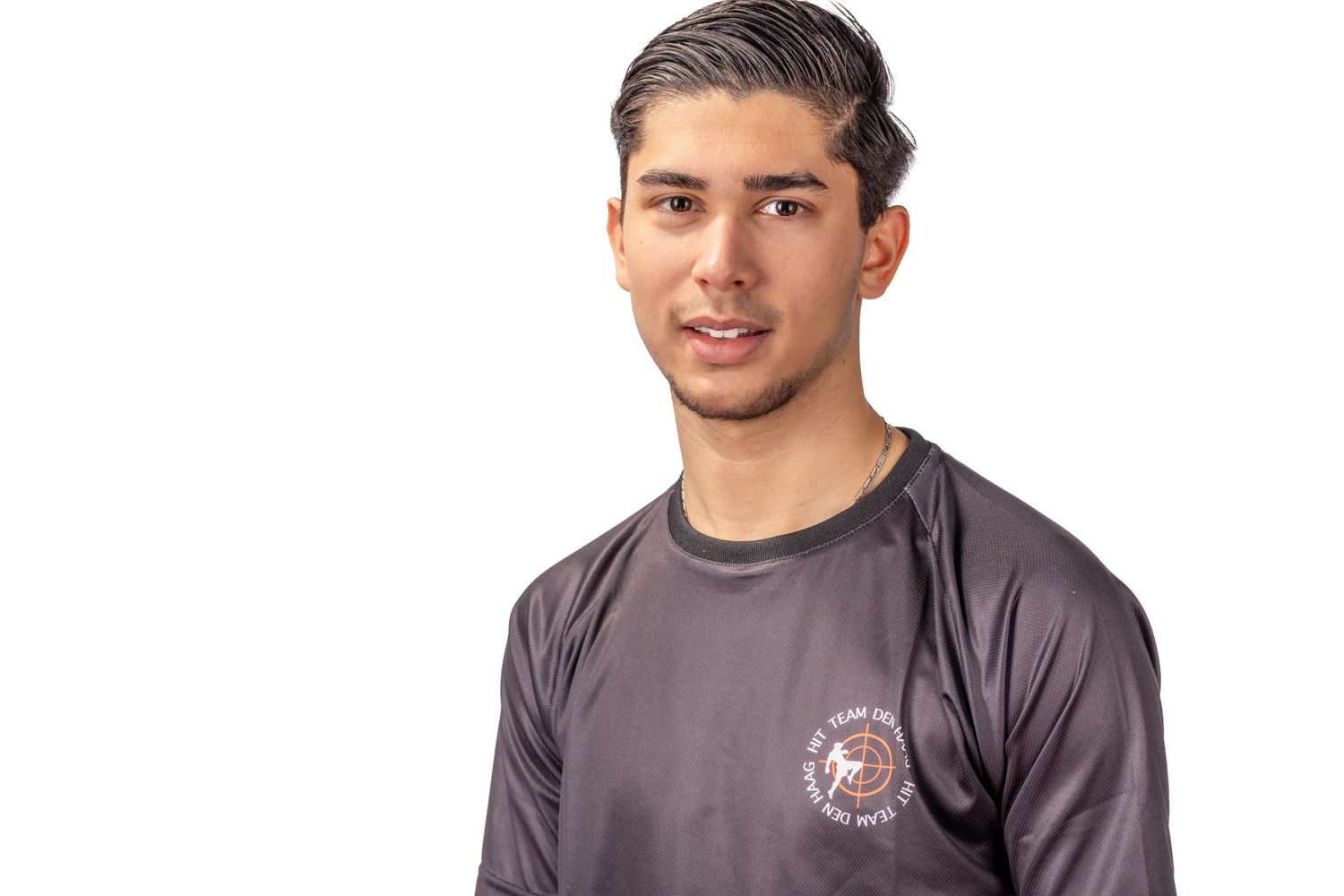 A person wearing a gray t-shirt with a logo smiles while posing for a casual portrait photo.