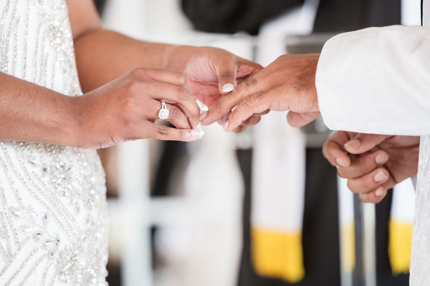 Close-up of hands exchanging wedding rings during ceremony.
