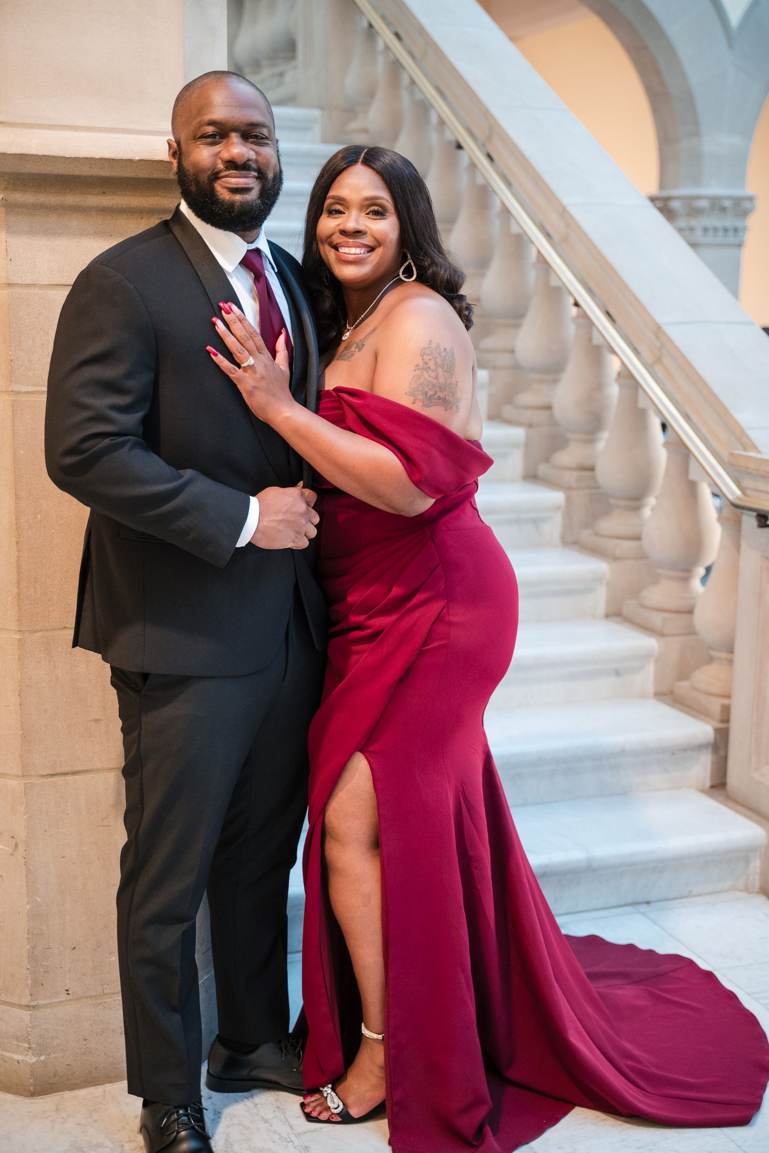 Couple poses on grand stone staircase during engagement shoot.