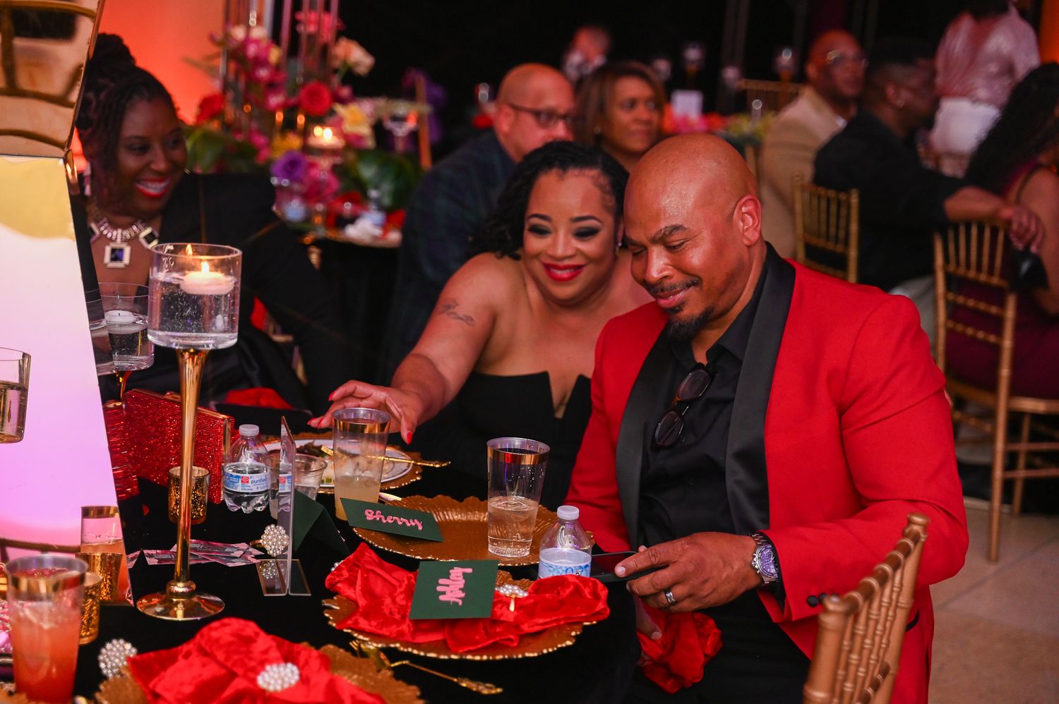Guests enjoying dinner and conversation at tables decorated in red and black.