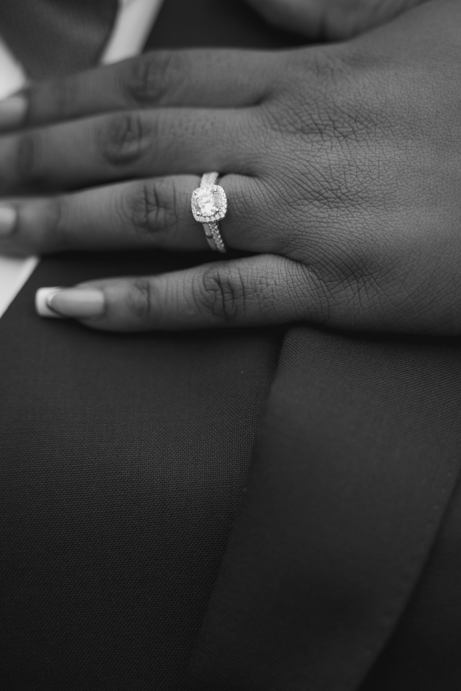 Close-up black and white shots of engagement ring and wedding band on hand.
