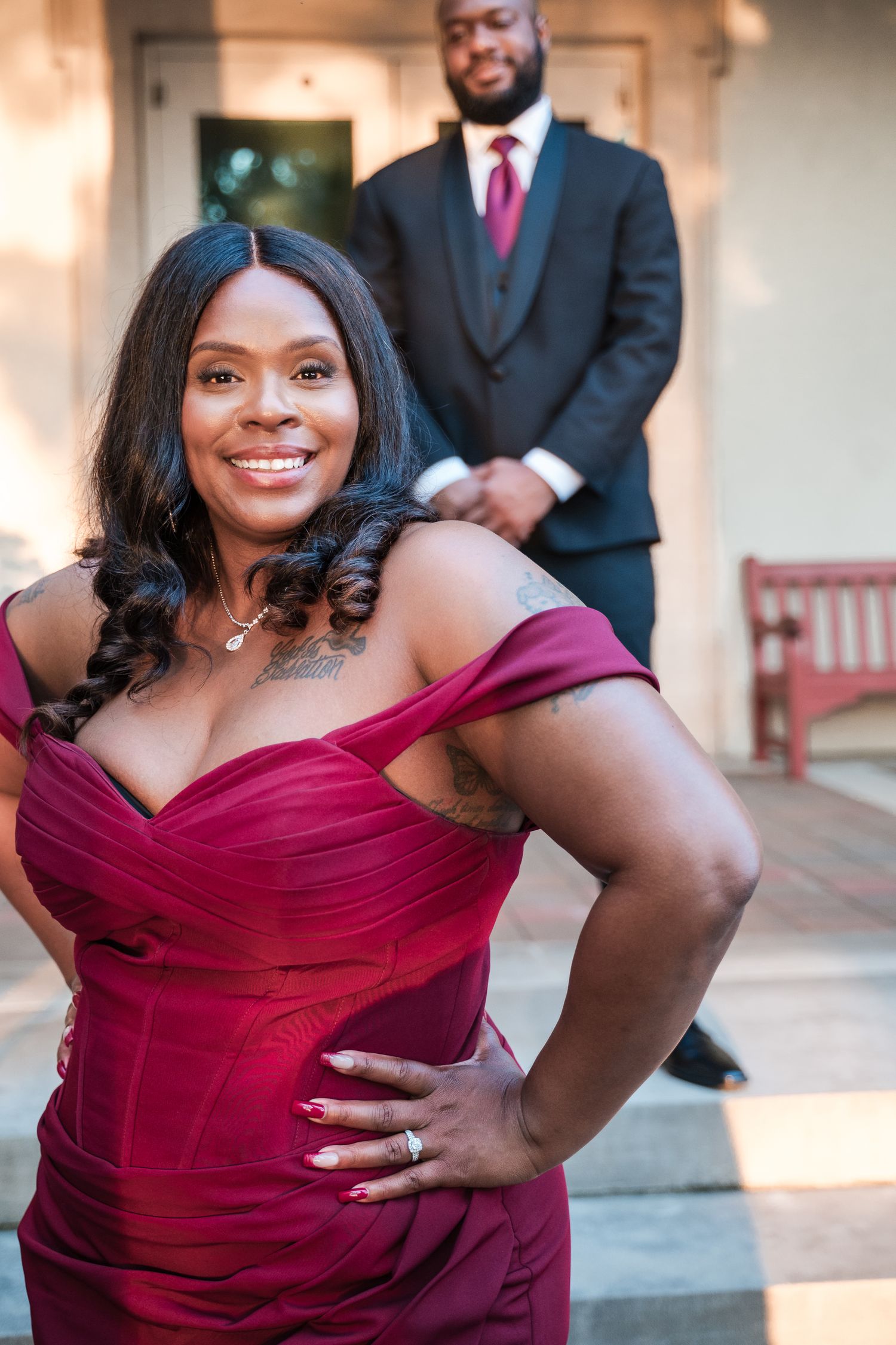 Woman in burgundy off-shoulder dress poses elegantly during photoshoot.