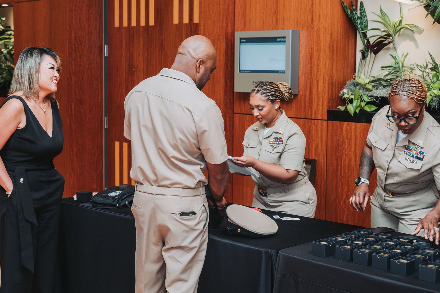 Event staff in beige uniforms manage equipment at a DJ station.