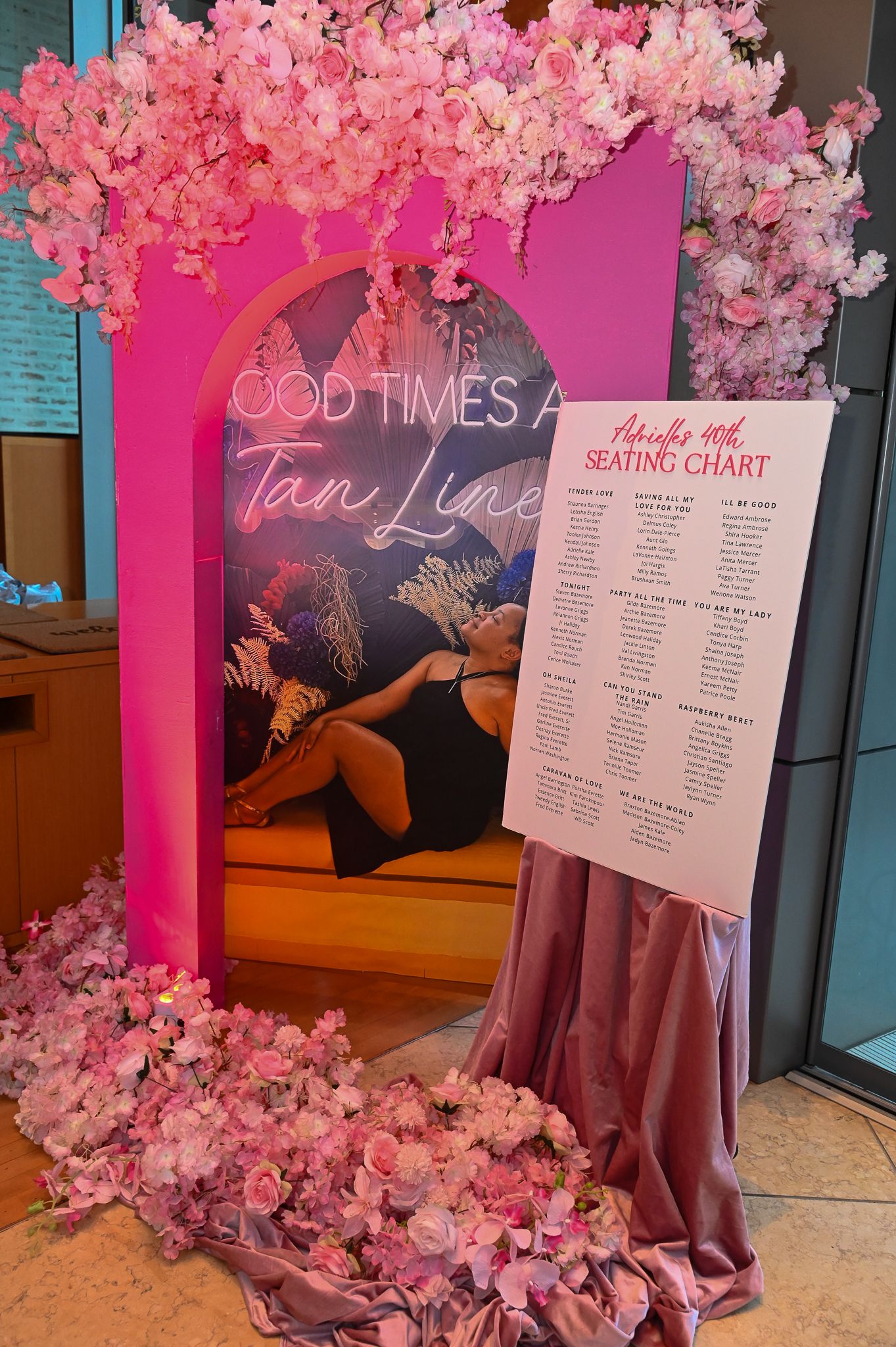Elegant event setup with pink cherry blossoms and seating chart display against turquoise walls.