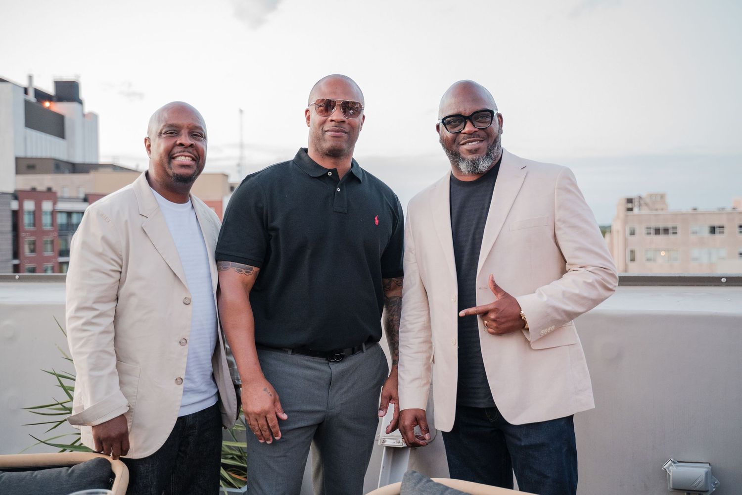 Three professionals in business attire posing together on a rooftop.