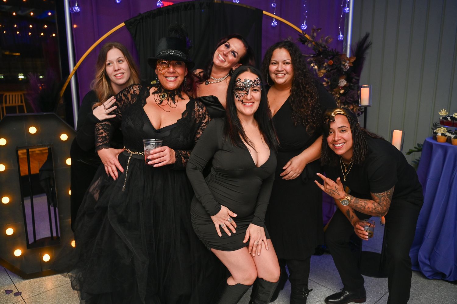 People dressed in black and red outfits gather together for a celebratory group photo.