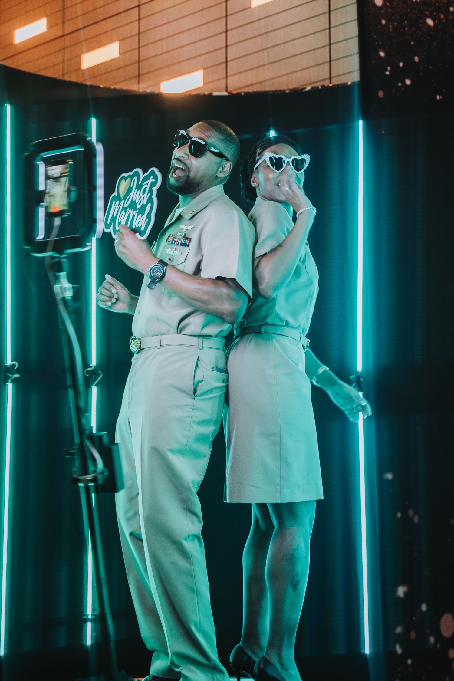 Healthcare workers in white uniforms stand in a dark room illuminated by vertical turquoise neon lights.