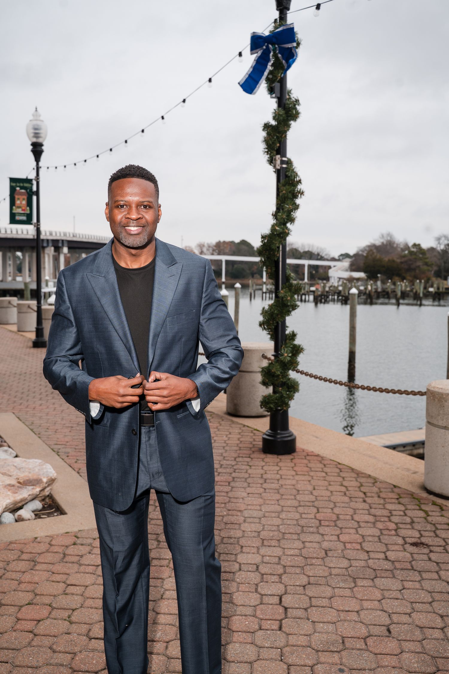 Professional portrait session on a brick waterfront boardwalk with decorative lamp posts.