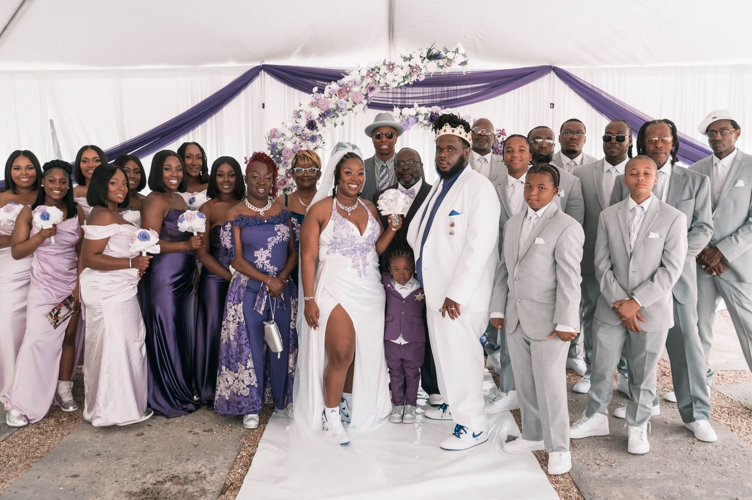 Large wedding party group photo with members wearing coordinated white and gray formal attire.