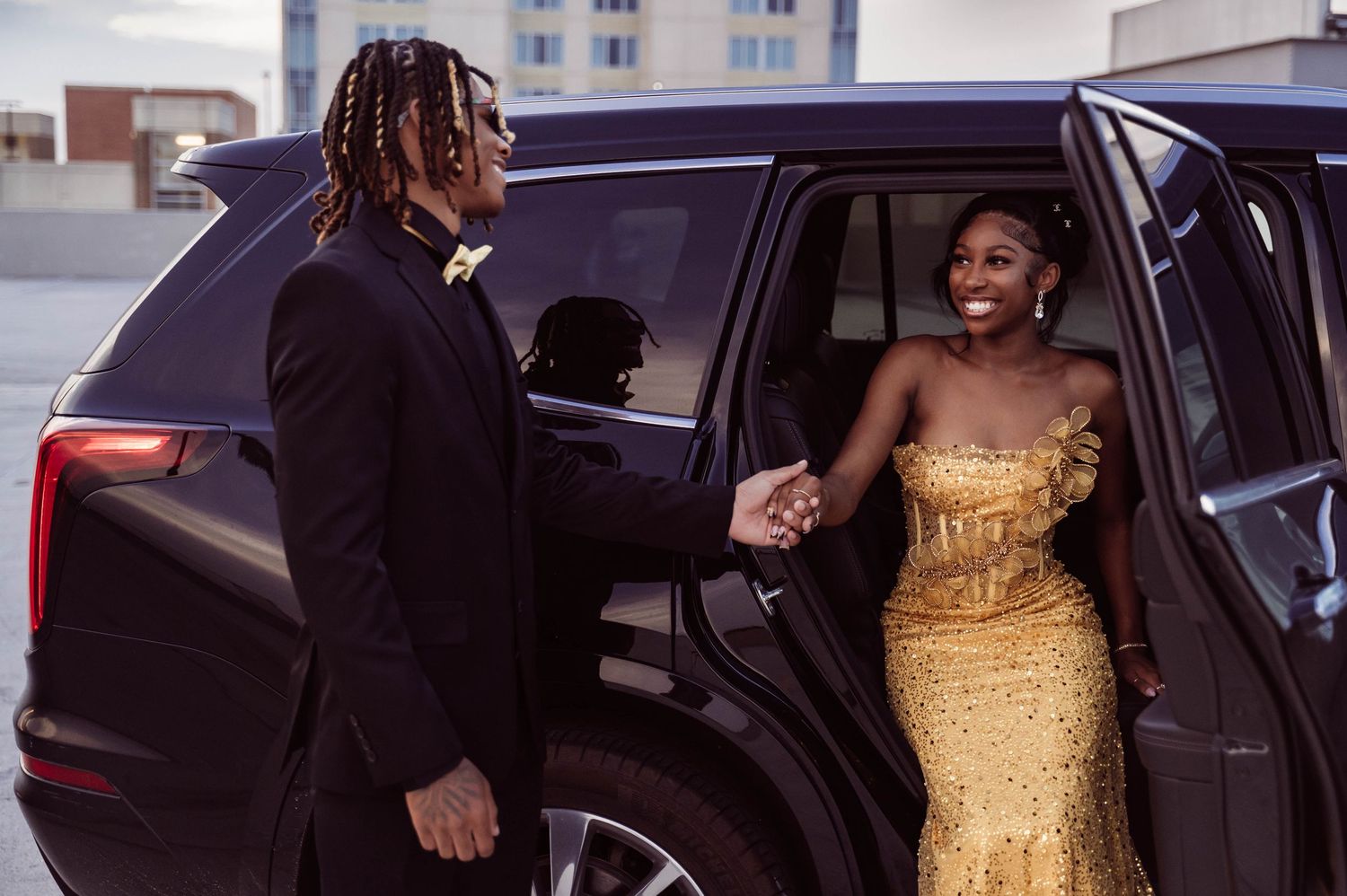 Guests in formal attire entering and exiting luxury vehicles outside a building.