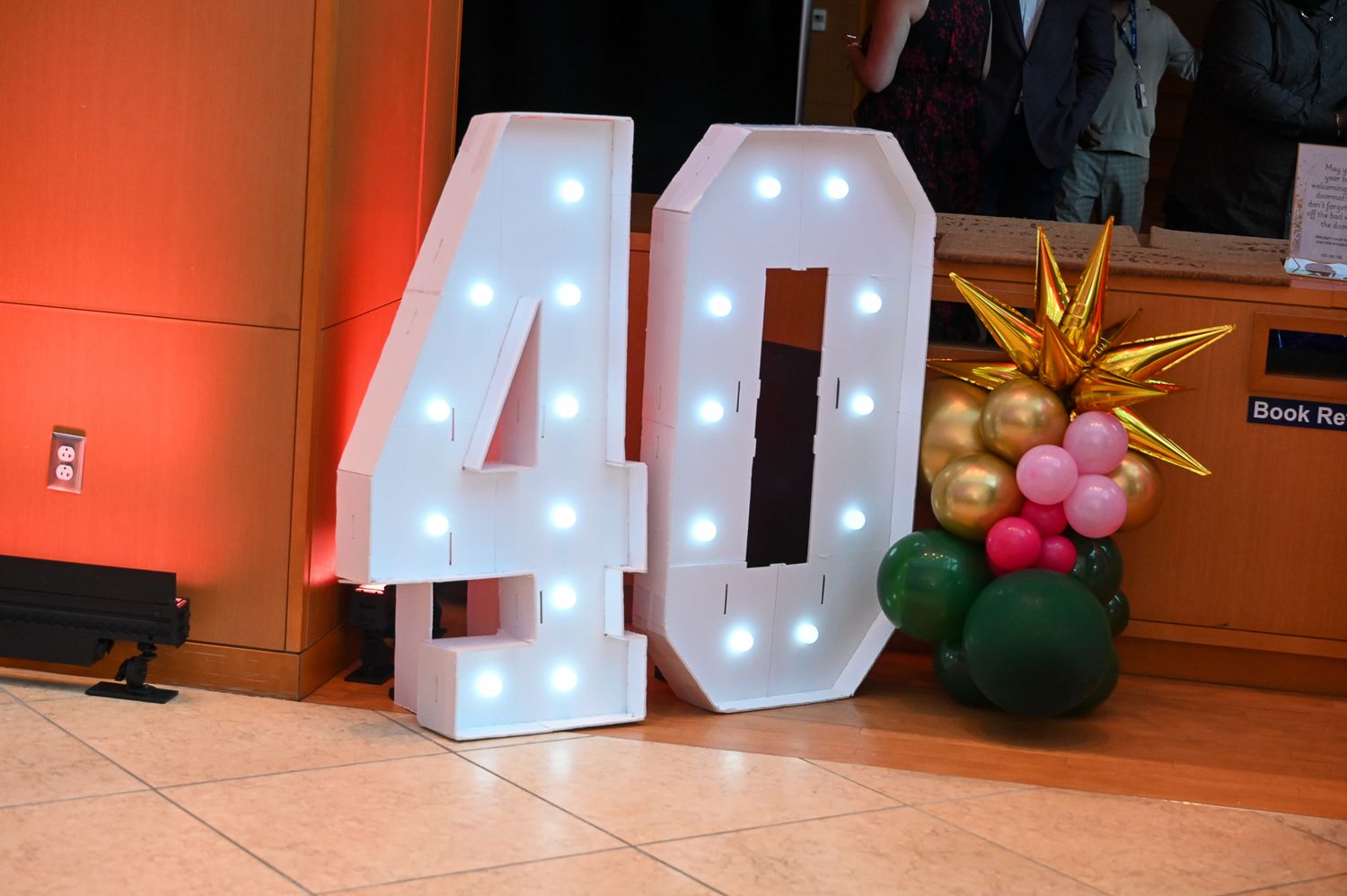 Large illuminated number 40 decorations displayed against an orange-lit wall at an event venue.
