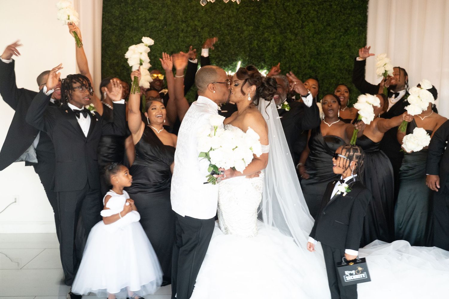 Wedding party in black and white attire poses during celebration.