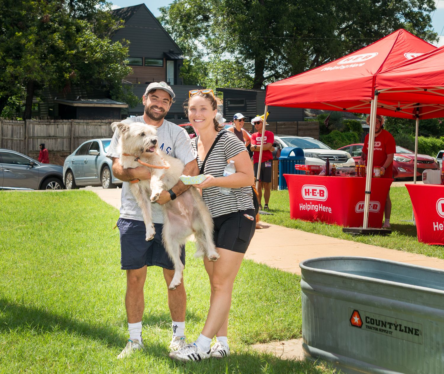 Dogs and their owners enjoying an outdoor event with red tents in the background.