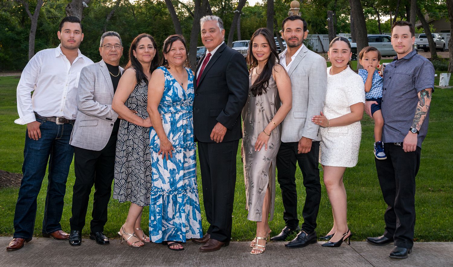A large family group in mixed formal attire poses together on a garden path.