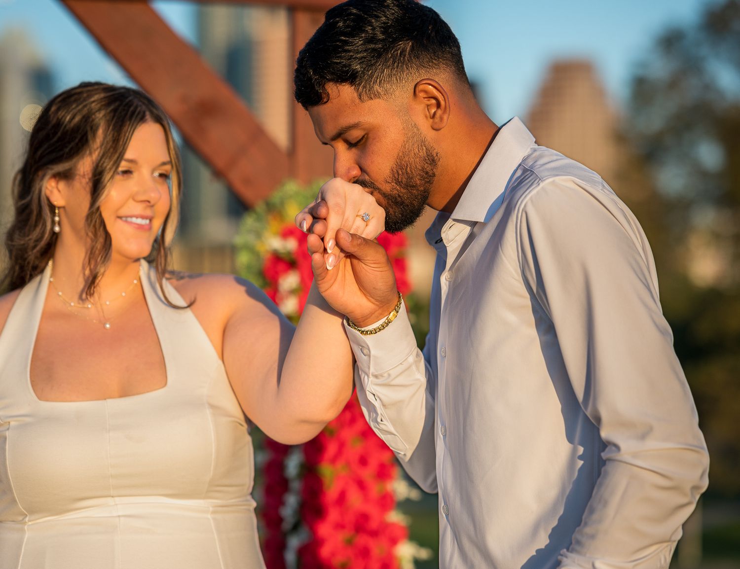 A couple in white clothing shares an intimate moment outdoors.
