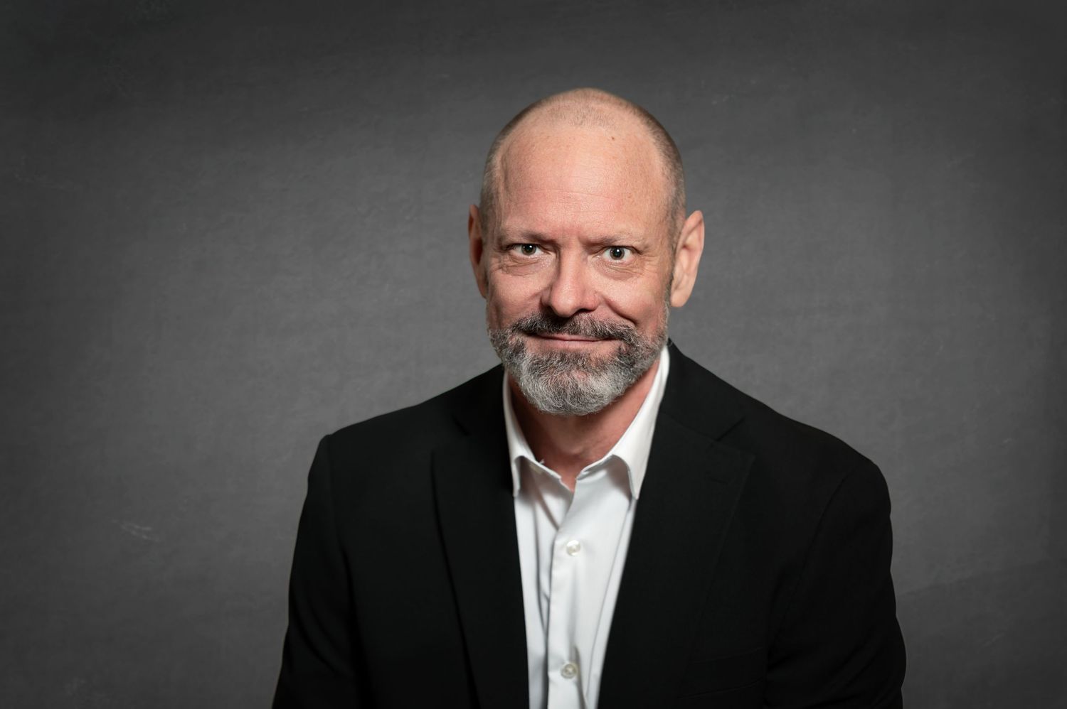 Professional headshot series of a man in a black suit against a dark gray background.