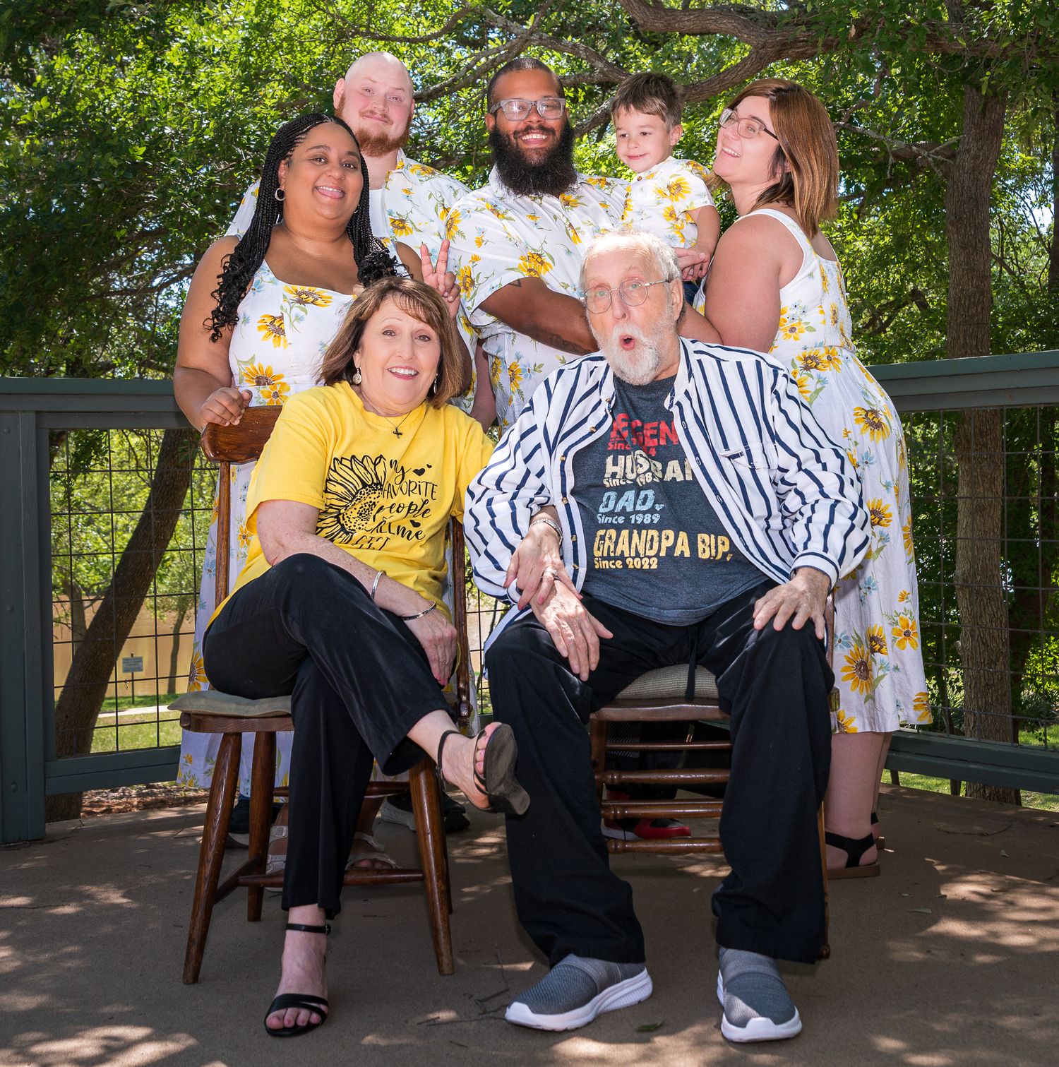 Family members seated on wooden bench during outdoor photo shoot.