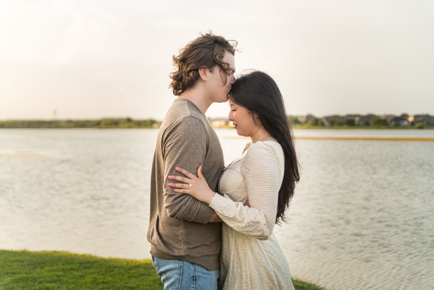 A romantic couple embraces by a serene waterfront during golden hour, creating a dreamy silhouette against the sunset.