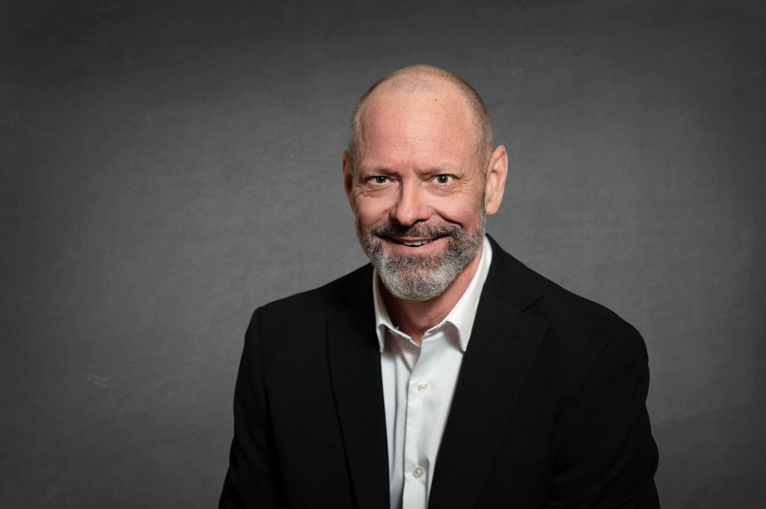 Professional headshot series showing a person in business attire against dark background with varying expressions.
