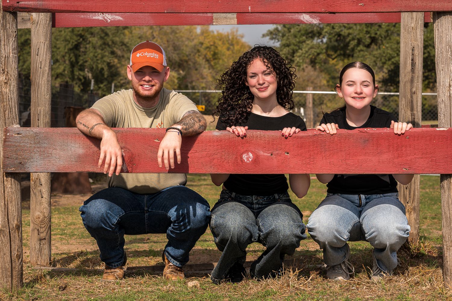 Group photo showing people sitting on a red wooden bench structure outdoors.