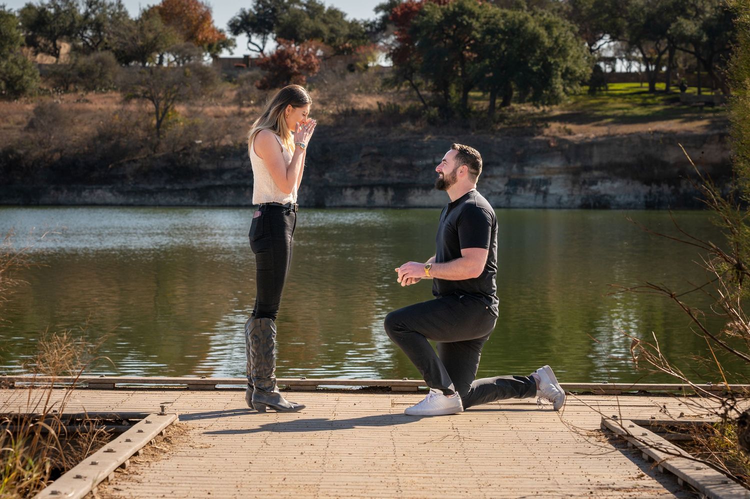 People exercising and stretching near a scenic lake surrounded by trees in a peaceful outdoor setting.