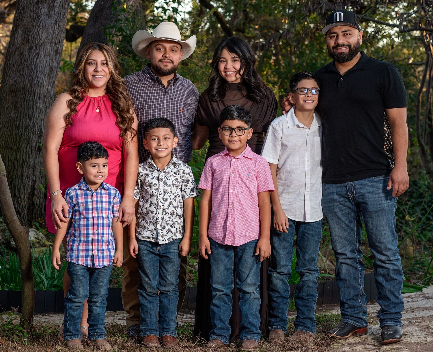 A group of people in casual western attire pose together outdoors against a natural backdrop.