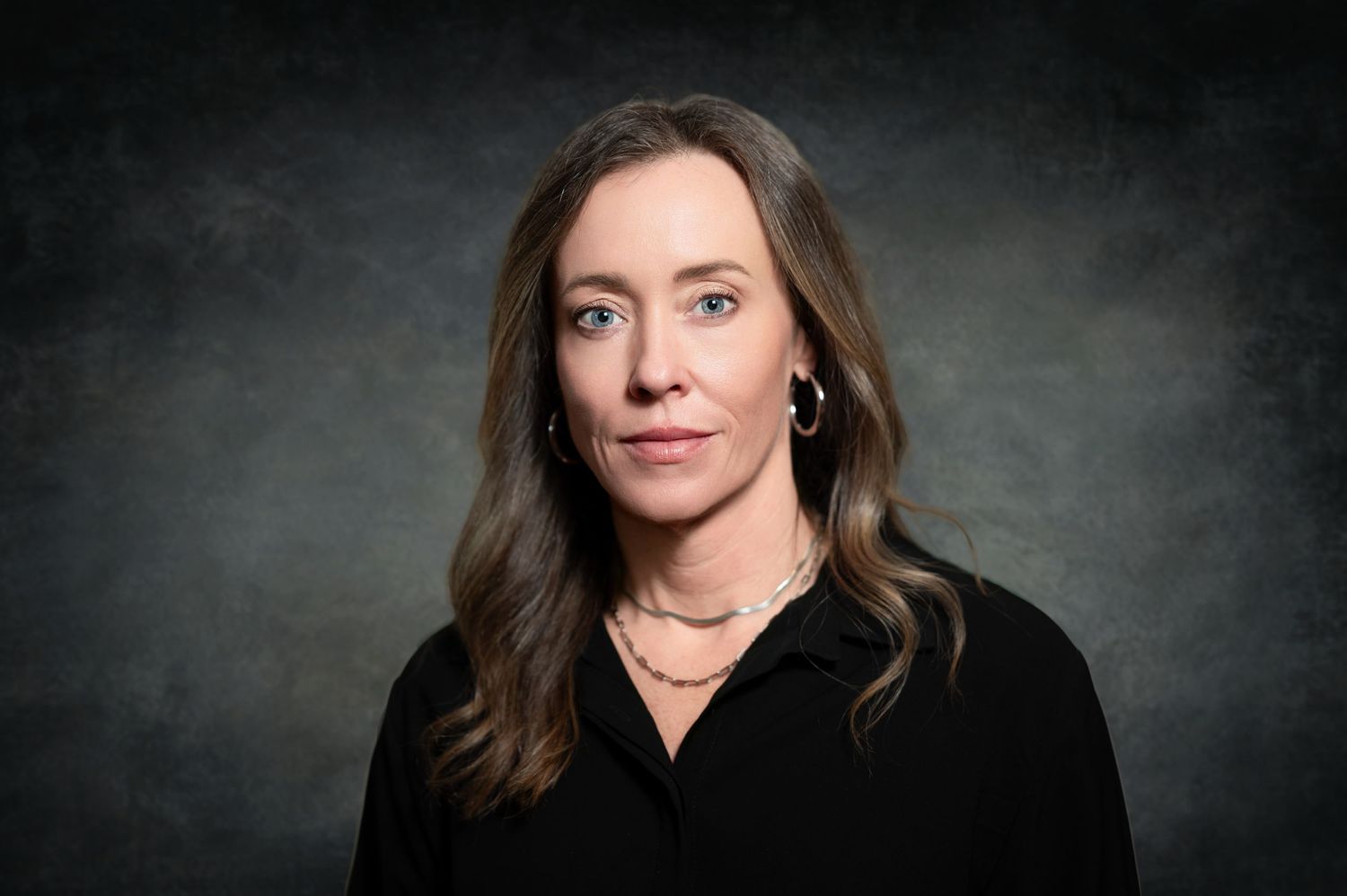 Professional dark backdrop portraits of person with brown hair wearing black attire.