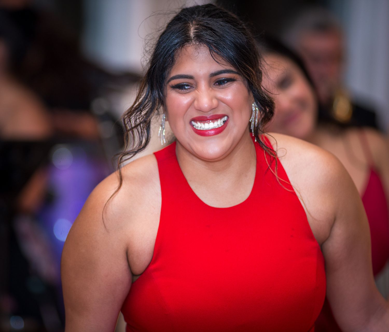 Woman in a vibrant red sleeveless dress enjoying herself at a formal gathering.