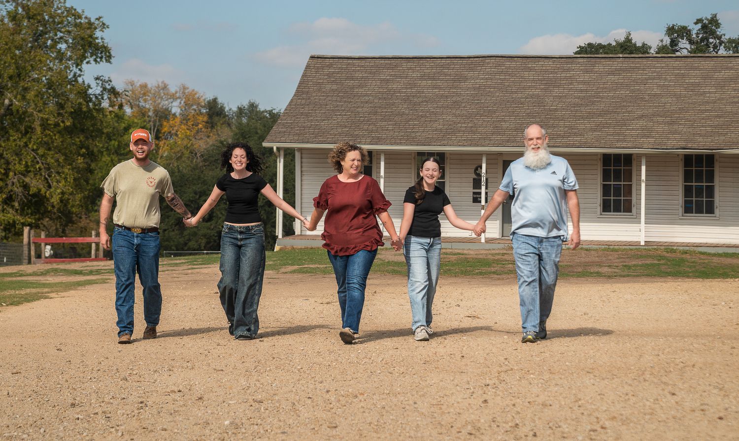 Family members walking together across open field near residential home.