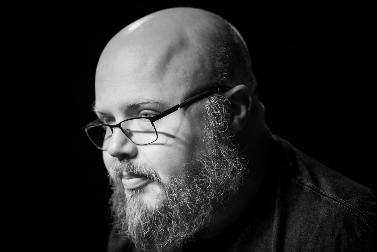 Dramatic black and white close-up portrait series showing partial face with glasses and beard.