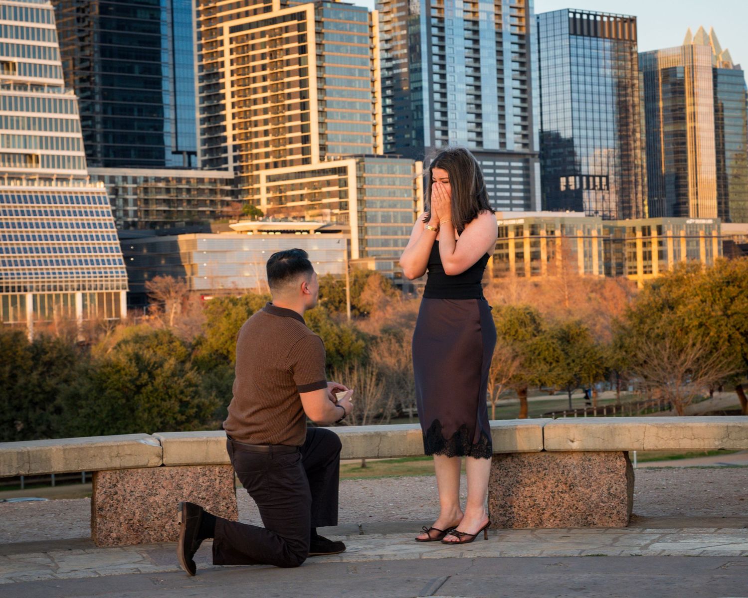 Romantic proposal scene with downtown Austin skyline at sunset along the boardwalk at Lady Bird Lake.