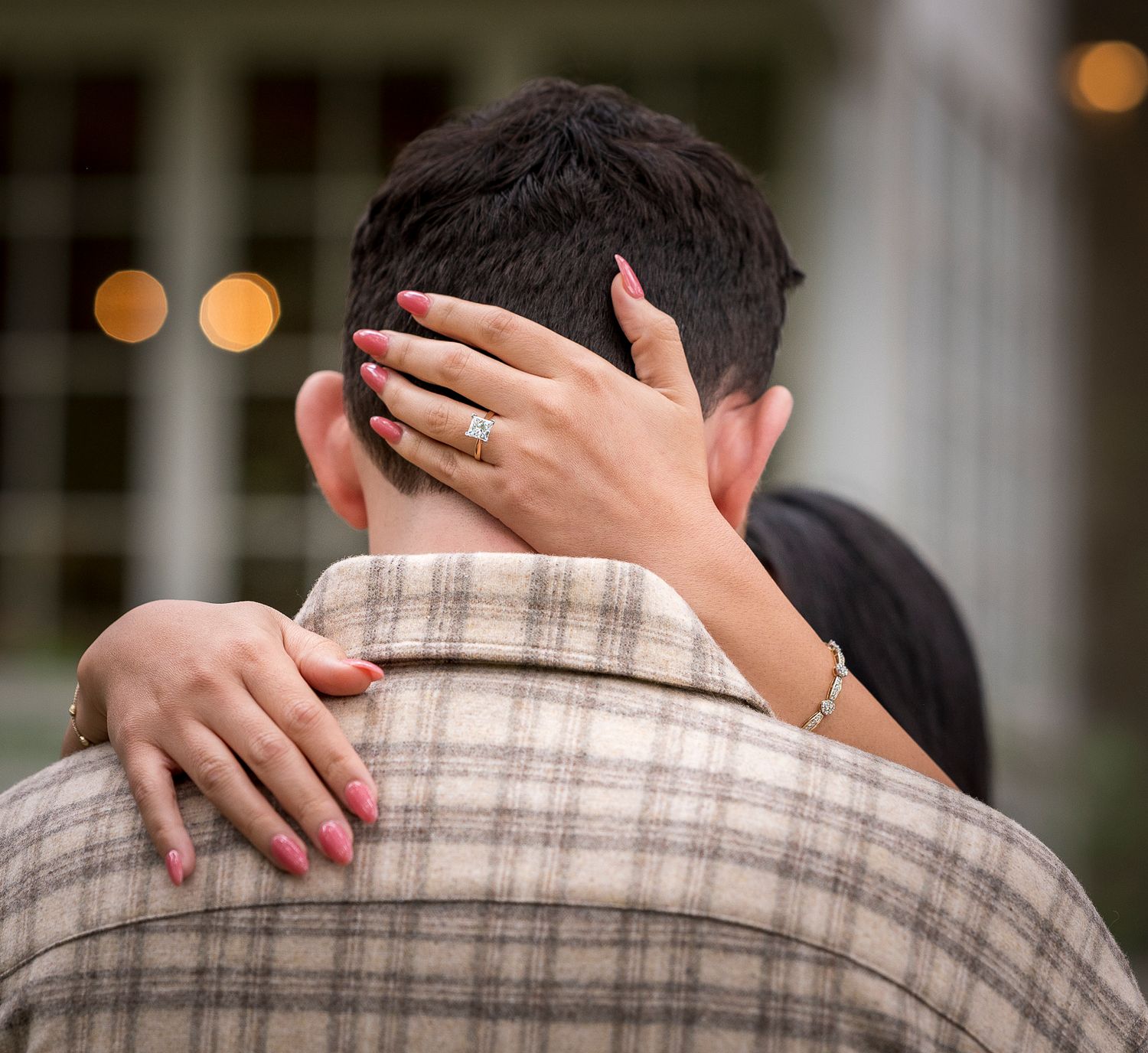 A newly engaged couple embraces in an intimate moment outside.