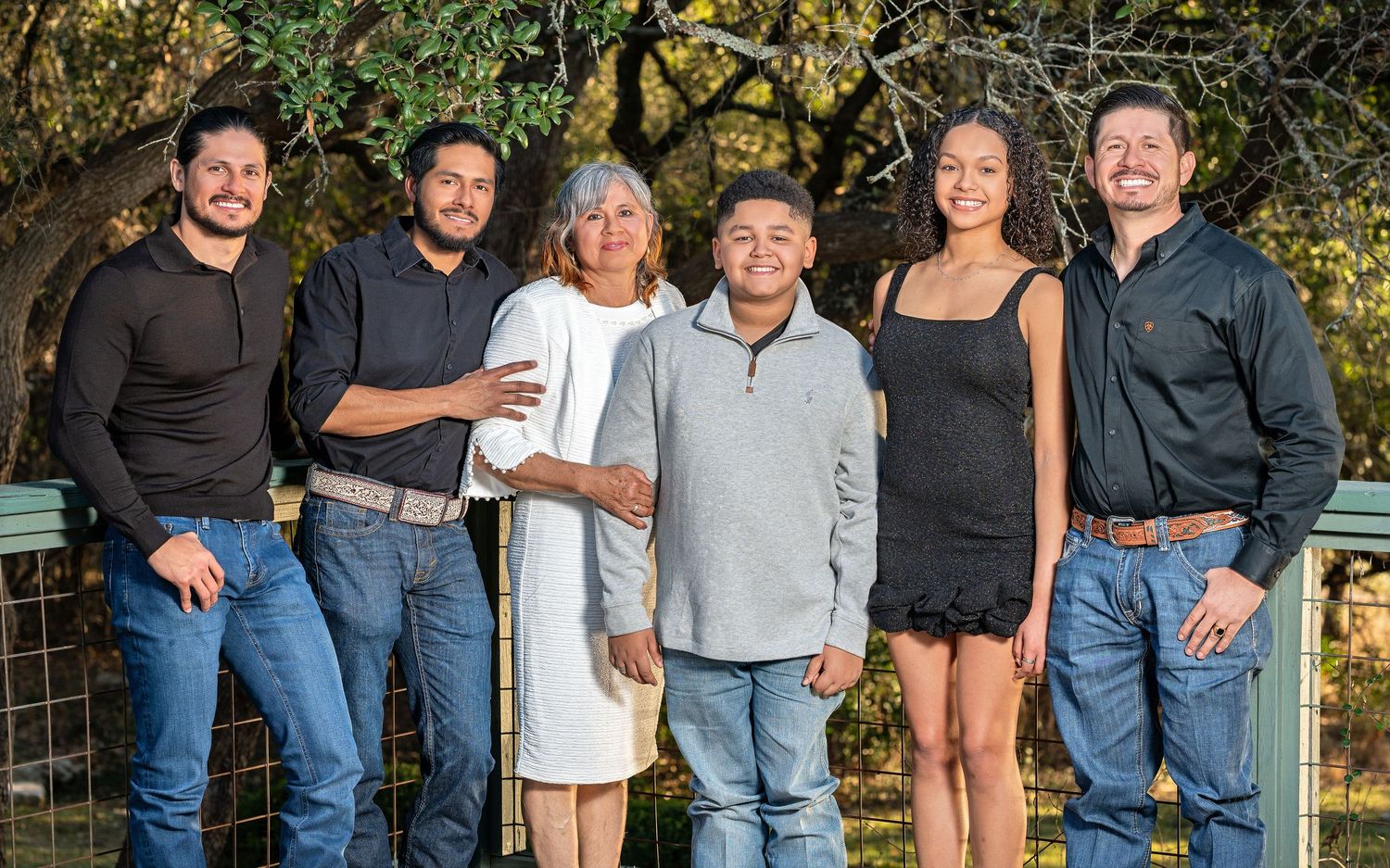 A casual family group portrait taken outdoors against a natural garden backdrop.