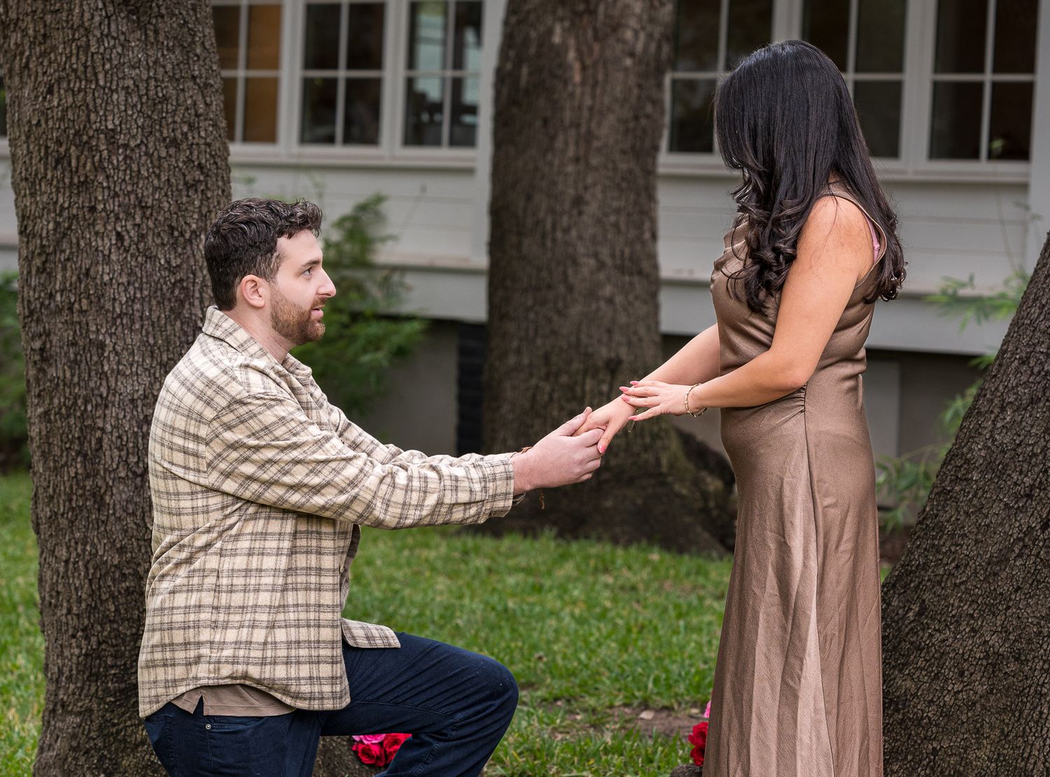 A proposal sequence in front of a house showing someone getting down on one knee.