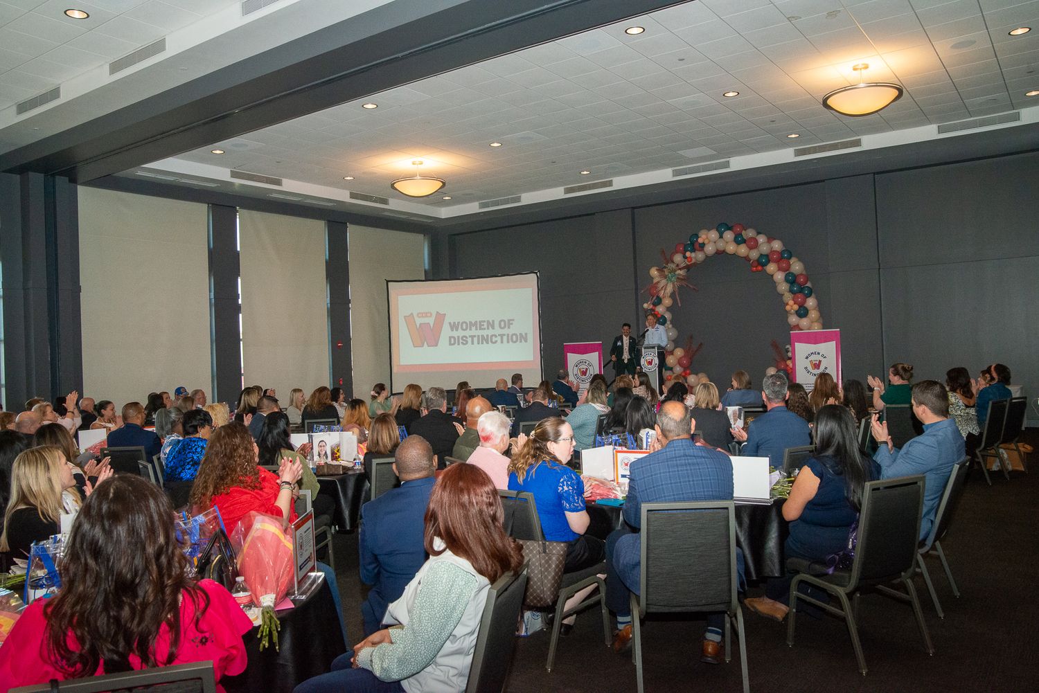 Conference room panorama showing multiple rows of tables with attendees during an event.