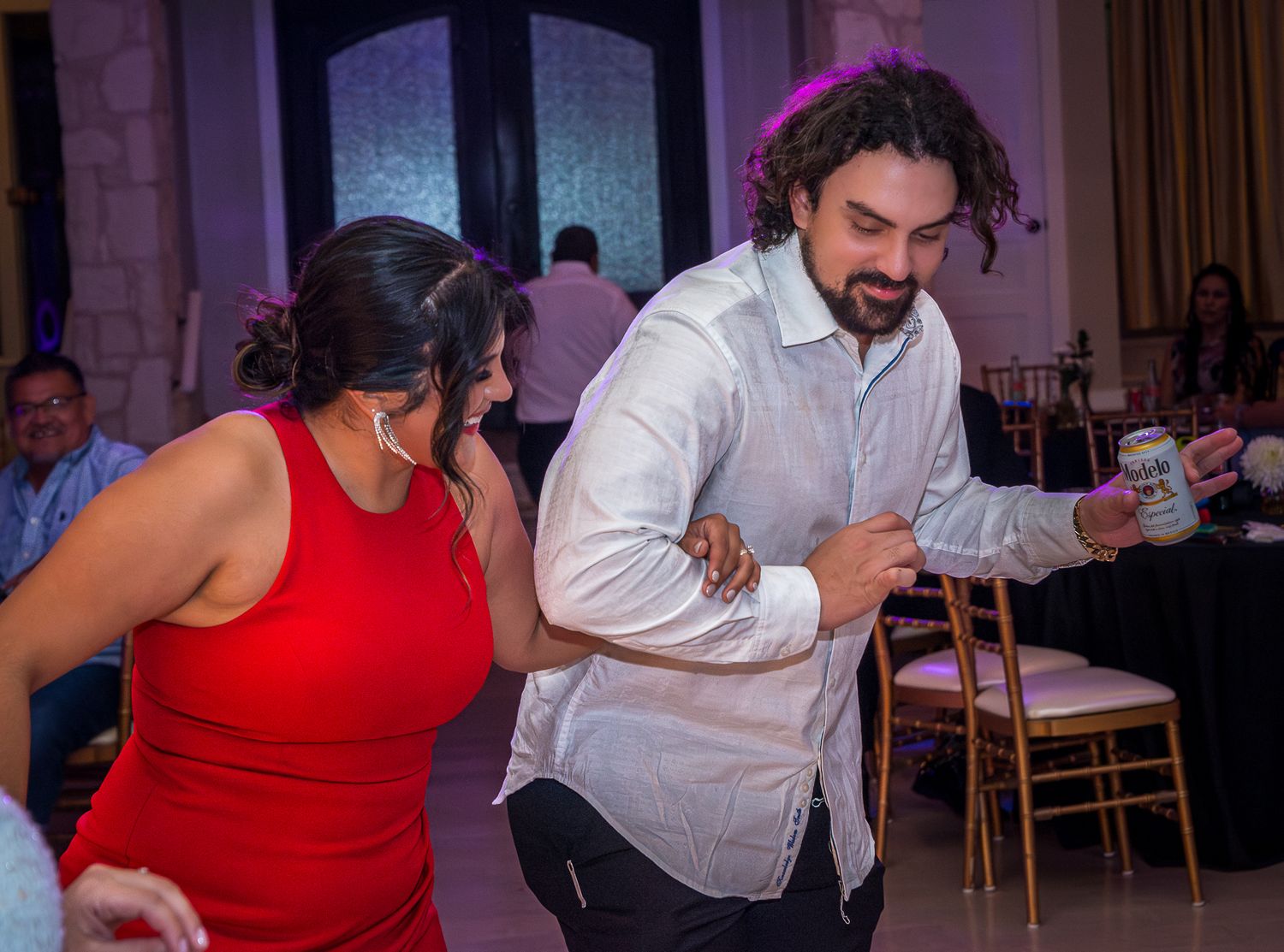 Couples dancing energetically at a party with formal attire.